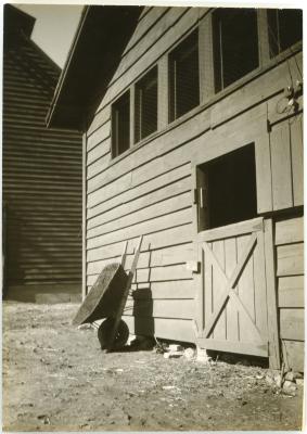 Untitled [Wheel barrow leaning against college barn]