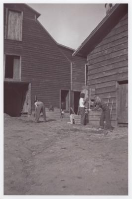 Students doing farm work next to barn and silos at Lake Eden campus